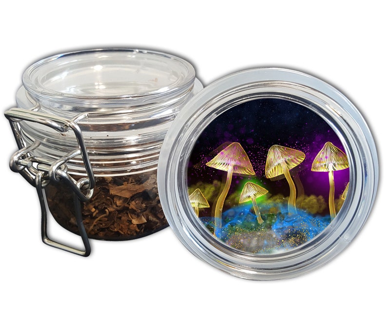 May include: A clear glass jar with a hinged lid, partially open, revealing dried leaves. The lid's interior features a colorful illustration of glowing mushrooms against a purple and blue background. The jar is designed for storage.