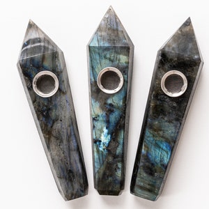 Op de afbeelding: Drie regenboogkleurige blauwe en zwarte labradorit kristallen pijpen met een zilveren metalen kom.