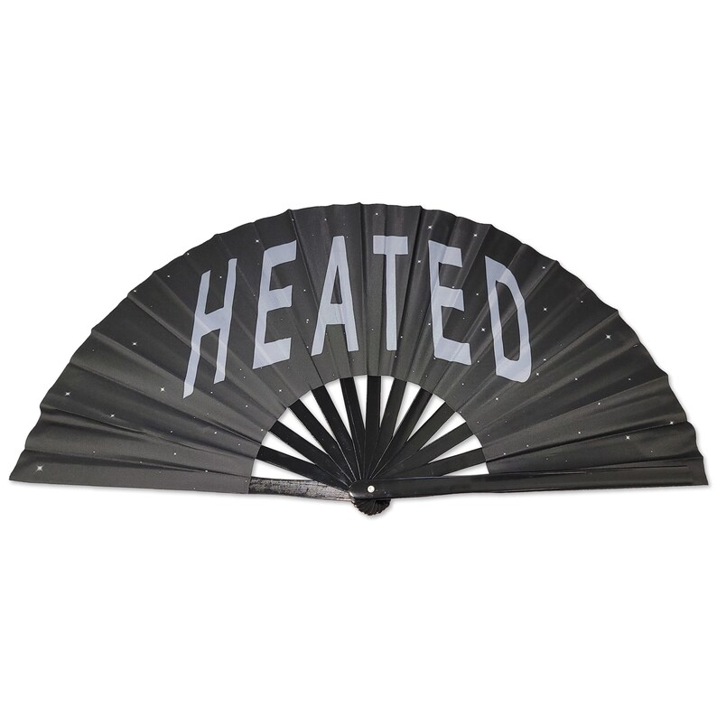 以下が含まれることがあります： 銀色のグリッターと「HEATED」という文字が印刷された黒い折りたたみ式扇子です。