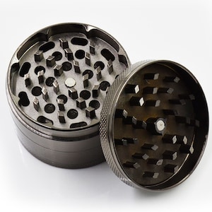 May include: A silver metal grinder with a textured surface and a circular design. The grinder has a top and bottom section, each with a series of teeth for grinding herbs.