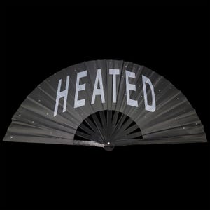 以下が含まれることがあります： 「HEATED」と白文字で書かれた黒い折りたたみ式の扇子です。