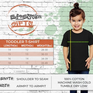 Pode incluir: Uma tabela de tamanhos para camisetas de crian&ccedil;as pequenas com medidas em polegadas e libras. A tabela mostra o comprimento, a largura e o peso para os tamanhos 2T, 3T, 4T e 5/6T. A tabela tamb&eacute;m inclui o texto "LENGTH: SHOULDER TO SEAM" e "WIDTH: ARMPIT TO ARMPIT".