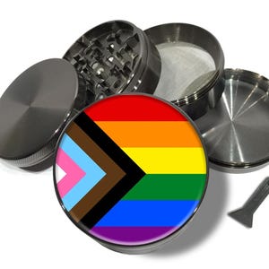 Peut inclure: Un broyeur métallique démonté avec un motif de drapeau arc-en-ciel Pride. Le broyeur est composé de plusieurs parties, dont un couvercle, une chambre de broyage, un tamis et une chambre inférieure. Un petit grattoir gris est également inclus.