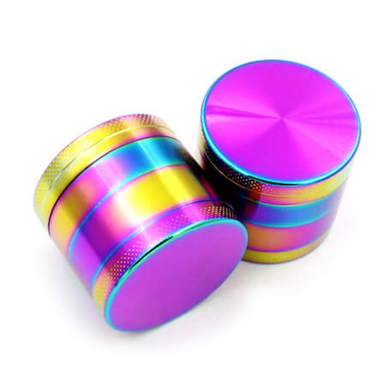 May include: Two rainbow-colored metal grinders with a purple top. The grinders have a striped pattern with yellow, blue, and green colors.