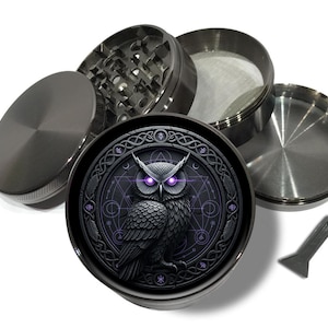 May include: A disassembled, dark gray metal herb grinder with a detailed owl design. The owl has purple eyes and is surrounded by geometric patterns. Includes a small scraper tool.