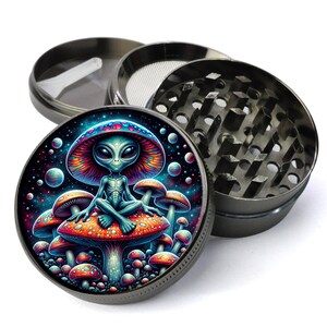 May include: A metal grinder with a colorful design featuring an alien sitting on a mushroom in a psychedelic space scene. The grinder has a top lid, a grinding chamber, and a screen.