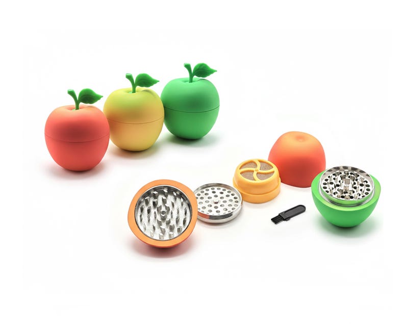 May include: A selection of apple-shaped herb grinders in red, yellow, and green. The grinders are taken apart, showing the metal grinding parts and a small brush. The design is fun and colourful.