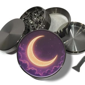 Pode incluir: Um moedor de metal desmontado com um design celestial. A peça superior apresenta uma lua crescente e estrelas contra um céu roxo. O moedor é feito de metal e inclui uma pequena ferramenta raspadora.