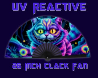 May include: A UV reactive fan with a colorful illustration of the Cheshire Cat from Alice in Wonderland. The fan is 26 inches (66 cm) wide and has a black handle. The cat is depicted with a wide grin and vibrant colors.