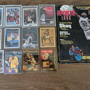 May include: A collection of twelve basketball trading cards featuring Shaquille O'Neal in various game poses, alongside a January 1994 issue of Collector's Sports Look magazine with a cover image of Shaquille O'Neal and the text The Pressures of Being Shaq.