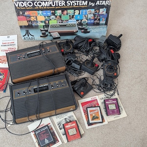 TWO Atari 2600 CONSOLES W/ GAMES, Joysticks, instructions, paddle controls, & box