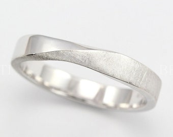 May include: A silver wedding band with a twisted design. The band has a brushed finish.