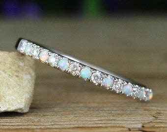 May include: A delicate silver band ring with a row of small white opals and diamonds.