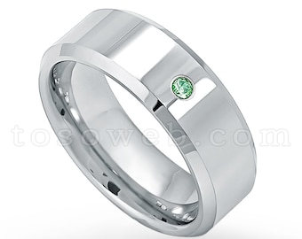 May include: A silver wedding band with a single green gemstone set in the center.