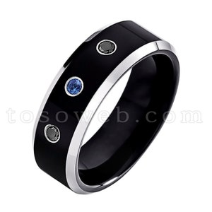 May include: A black tungsten carbide ring with a silver band and three gemstones. The ring has two blue gemstones and one black gemstone.
