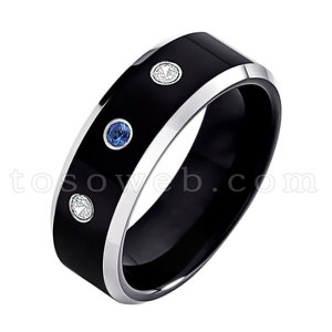 May include: A black tungsten carbide ring with a silver band and three gemstones. Two of the gemstones are blue and one is white.