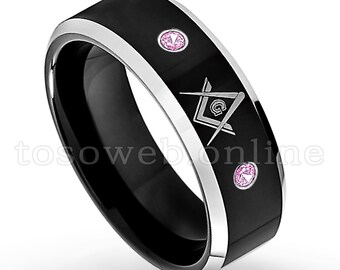 May include: Black tungsten carbide ring with a silver-toned Masonic symbol and three pink cubic zirconia stones.