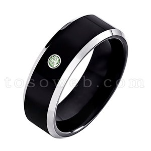 May include: A black tungsten carbide ring with a silver band and a small green gemstone.