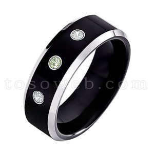May include: A black tungsten carbide ring with a silver band and three small gemstones. The gemstones are a light green, a clear white, and another clear white.