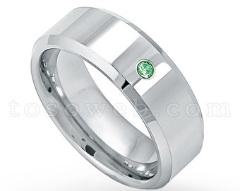 May include: A silver wedding band with a single green gemstone set in the center.