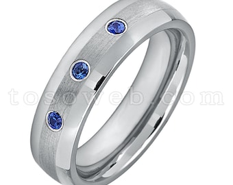 May include: A silver tungsten carbide ring with three blue sapphire gemstones set in the band.