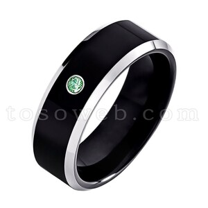 May include: A black tungsten carbide ring with a silver band and a single green gemstone.