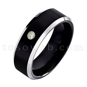 May include: A black tungsten carbide ring with a silver band and a small green gemstone.