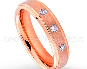 May include: Rose gold wedding band with three small pink gemstones set into the band.