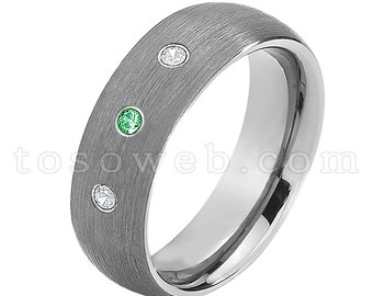 Pode incluir: Uma aliança de prata escovada com três pedras preciosas. A aliança tem dois pequenos diamantes redondos e uma pedra preciosa verde esmeralda.