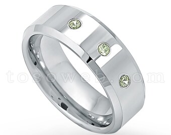 May include: A silver wedding band with three green gemstones set into the band.