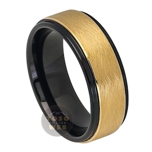 May include: A black and gold tungsten carbide ring with a brushed finish. The ring has a black band with a gold band on top.