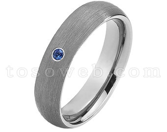 Pode incluir: Uma aliança de prata escovada com uma única pedra de safira azul.