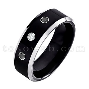 May include: A black tungsten carbide ring with a beveled edge and three small gemstones. Two of the gemstones are white and one is black.