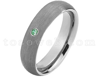 Pode incluir: Uma aliança de prata escovada com uma única gema verde engastada na banda.