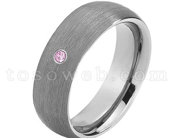 Pode incluir: Uma aliança de prata escovada com uma única gema rosa engastada no metal.