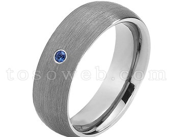 Pode incluir: Uma aliança de prata escovada com uma única pedra de safira azul.