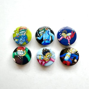 May include: Six circular badges featuring illustrations of divers. Each badge shows a diver wearing a diving mask and snorkel. The divers are depicted in blue, pink, green, and yellow diving suits against various backgrounds.