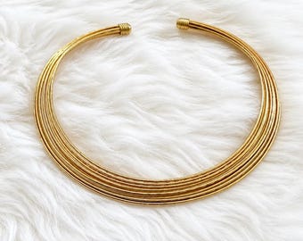 Minimalist 1970’s rigid torque-style choker necklace featuring a polished gold-tone finish