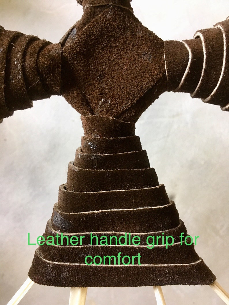 May include: Close-up of a brown leather handle grip. The grip is made of layered strips of leather, forming a cone shape. The text "Leather handle grip for comfort" is visible in green.