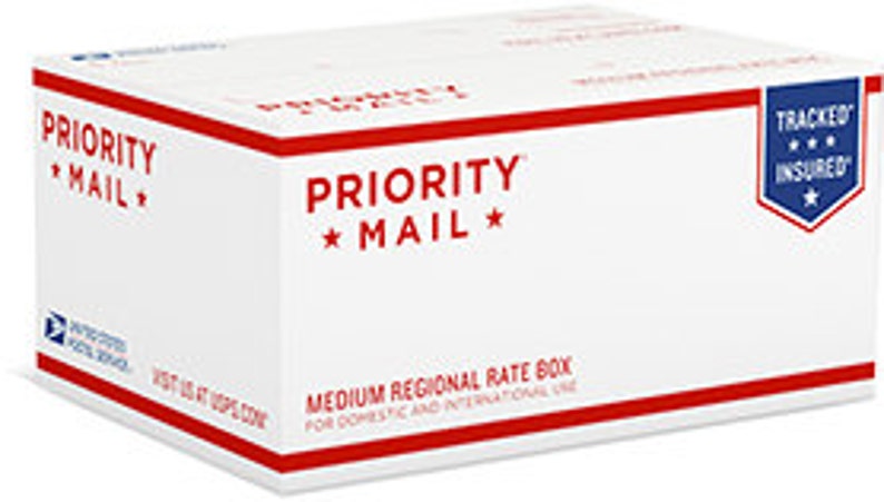 May include: A white Priority Mail box with red stripes and text. The box reads "PRIORITY MAIL" and "MEDIUM REGIONAL RATE BOX." A blue and white USPS logo is visible on the side, along with a "TRACKED" and "INSURED" emblem.