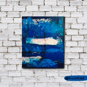 May include: Abstract painting with blue, white, and pink paint strokes on a canvas. The painting has a textured surface and a dark blue background.