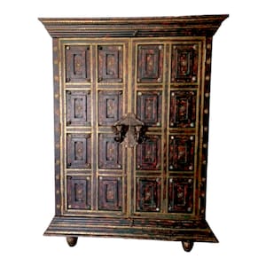 May include: A dark brown wooden cabinet with intricate gold detailing and brass accents. The cabinet has two doors with ornate brass handles and a decorative design on the front.