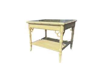 May include: A light beige bamboo-style side table with a glass top and a lower shelf. The table has a rectangular shape with decorative bamboo-style legs and supports. The design is reminiscent of a tropical or coastal aesthetic.