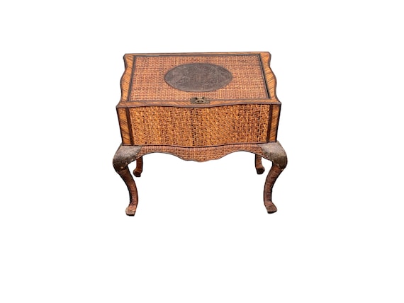 Wrapped wicker with cabriolet legs treasure chest with carved metal palm plaque.