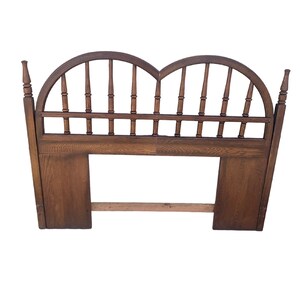 May include: A vintage wooden headboard with a dark brown finish. The headboard features two arched sections with vertical spindles and decorative finials. The lower portion has a rectangular design.