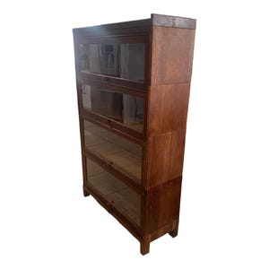 May include: A dark brown wooden bookcase with four glass shelves. The bookcase has a traditional design with a slightly curved front.