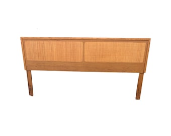 May include: A wooden headboard with a woven cane panel. The headboard has a simple design with two vertical supports.