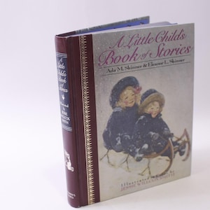 May include: A Little Child's Book of Stories. The book has a burgundy spine and cover with gold accents. The cover features an illustration of two children in winter clothing. The title and author's names are printed on the cover.