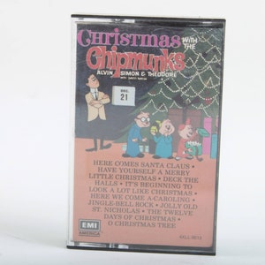 May include: A vintage cassette tape featuring the Alvin and the Chipmunks Christmas album. The cassette tape cover features a cartoon illustration of Alvin, Simon, and Theodore standing in front of a Christmas tree. The text on the cover reads "Christmas with the Chipmunks Alvin Simon & Theodore" and includes a list of songs on the album.