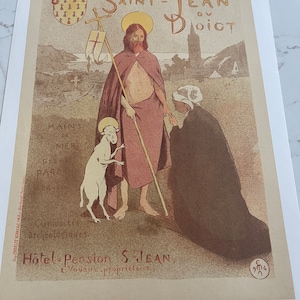 May include: A vintage poster advertising a hotel and pension called "Hotel Pension S Jean" in Saint-Jean du Doigt, France. The poster features a depiction of Saint John the Baptist with a lamb, and a woman kneeling before him. The poster is printed in shades of brown, yellow, and red.